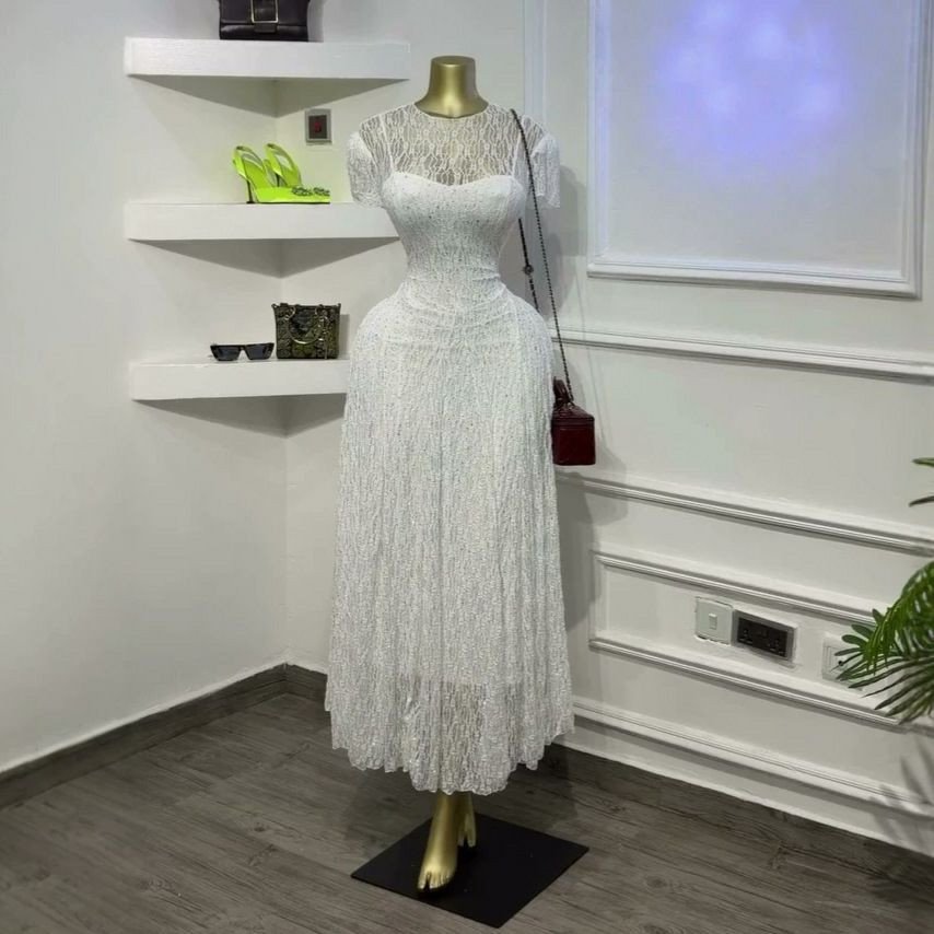 Robe midi en dentelle blanche qui présente un délicat haut transparent à manches courtes.